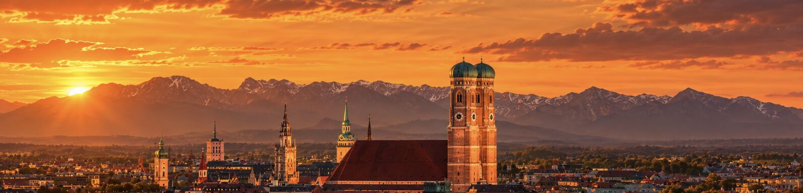 Münchner Skyline mit Frauenkirche vor den Alpen bei Sonnenuntergang
